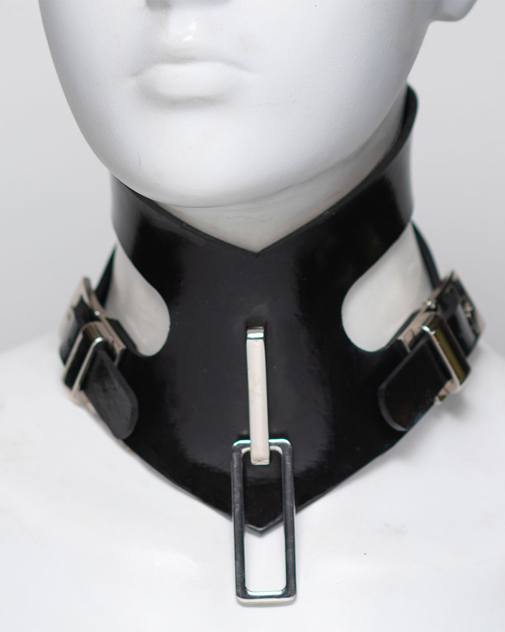 Black rubber collar with silver buckles on a mannequin head.