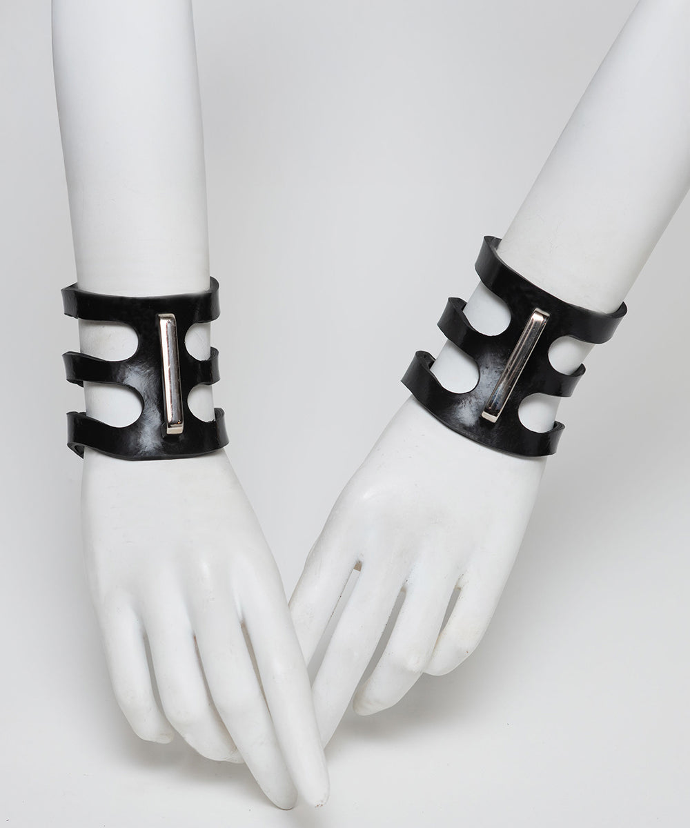 Black rubber cuffs on white mannequin hands against a white background