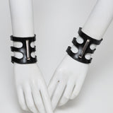 Black rubber cuffs on white mannequin hands against a white background