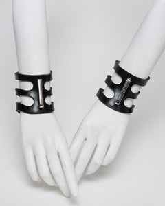 Black rubber cuffs on white mannequin hands against a white background
