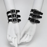 Black rubber bracelets with buckles on white mannequin hands against a light gray background