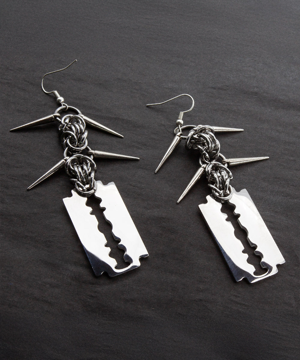 Razer Blade Dangle Earrings laying on a black background. 