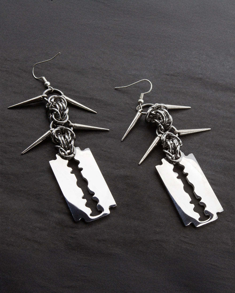 Razer Blade Dangle Earrings laying on a black background. 