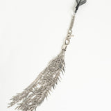 Silver feather-shaped flogger on a white background
