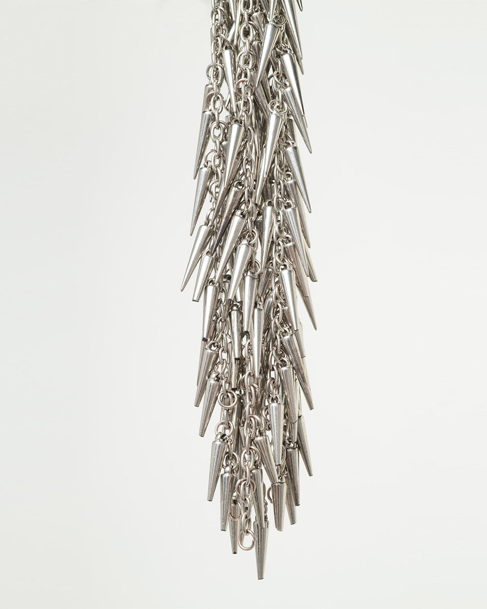 Silver spike and chain flogger close up on a light gray background