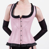Pink corset with black trim worn by a model on a white background