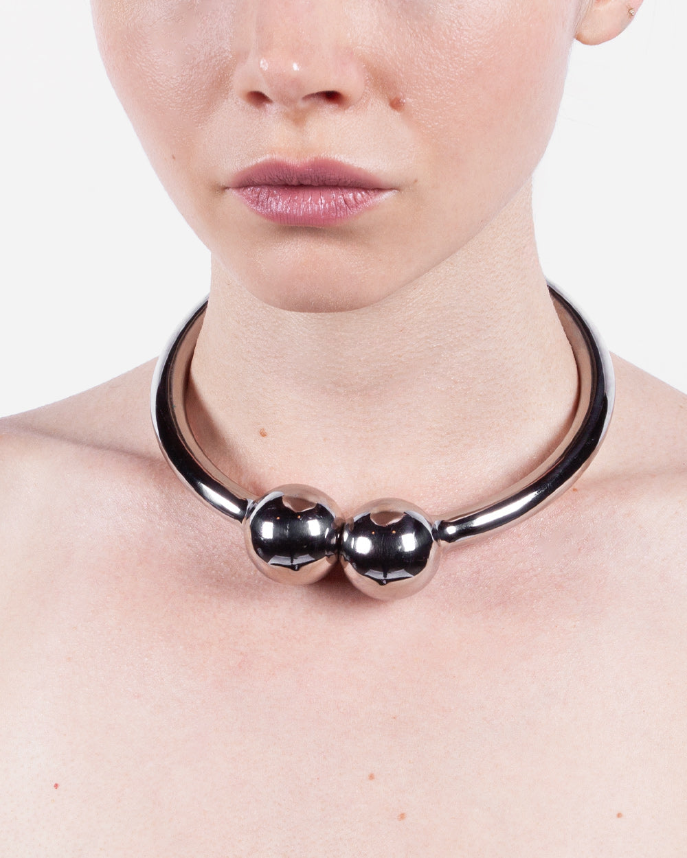 Person wearing a metallic necklace on a plain background