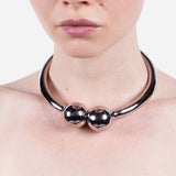 Person wearing a metallic necklace on a plain background