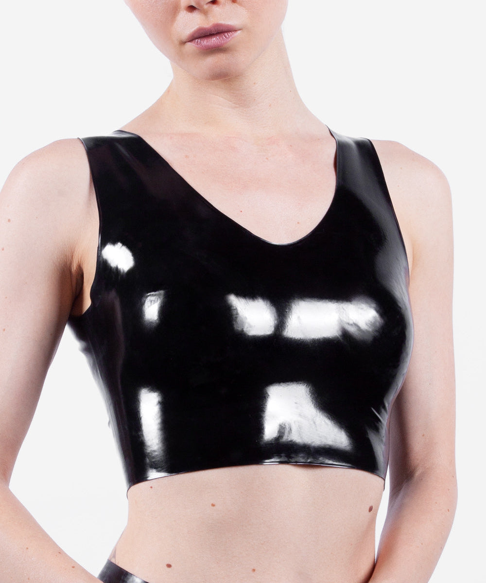 Person wearing a black latex crop top on a white background