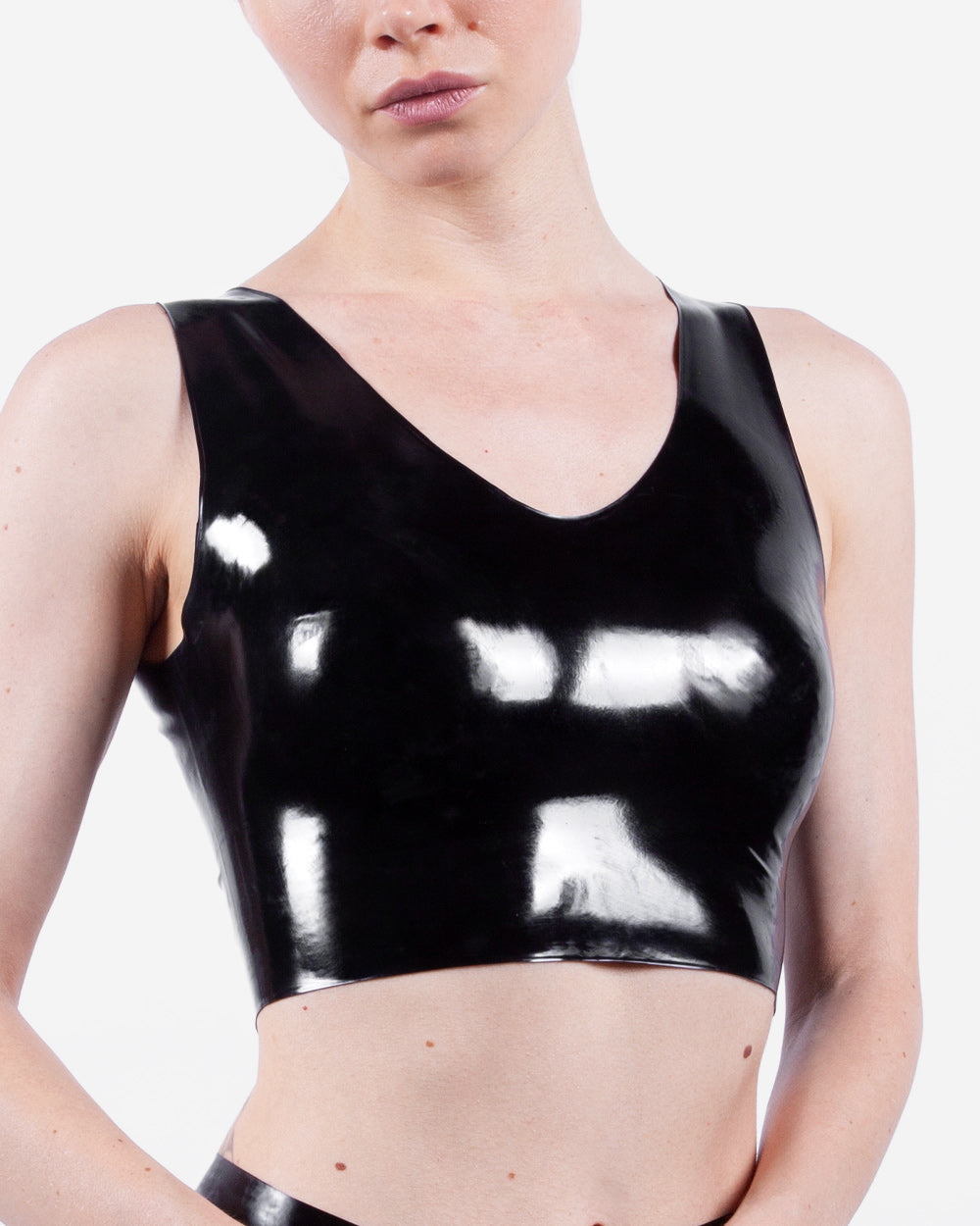 Person wearing a black latex crop top on a white background