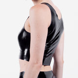 The side of a person wearing a black latex crop top on a white background