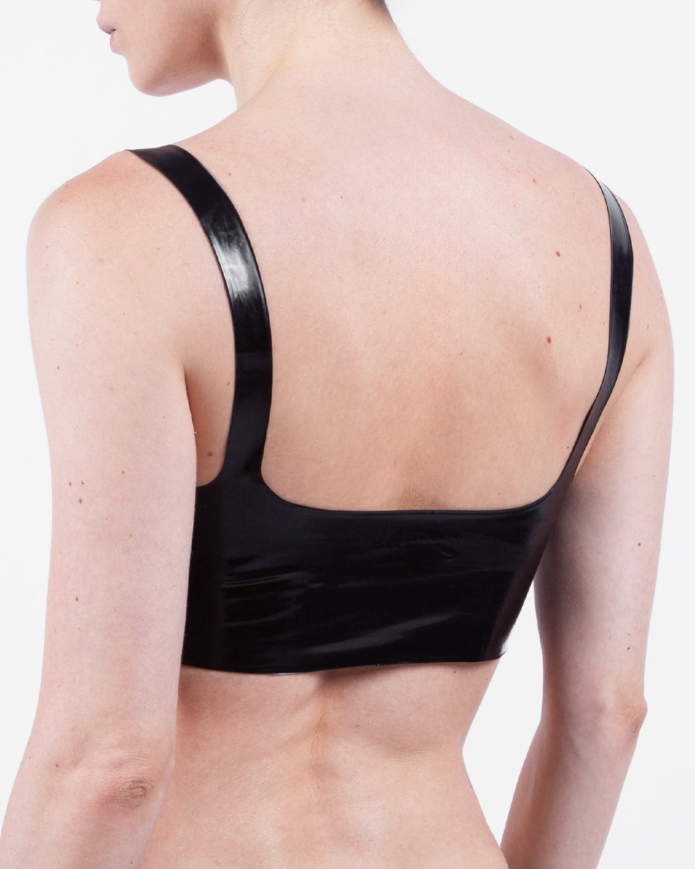 The back of a model is shown wearing a glossy latex basic halter bra, standing in front of a white background.