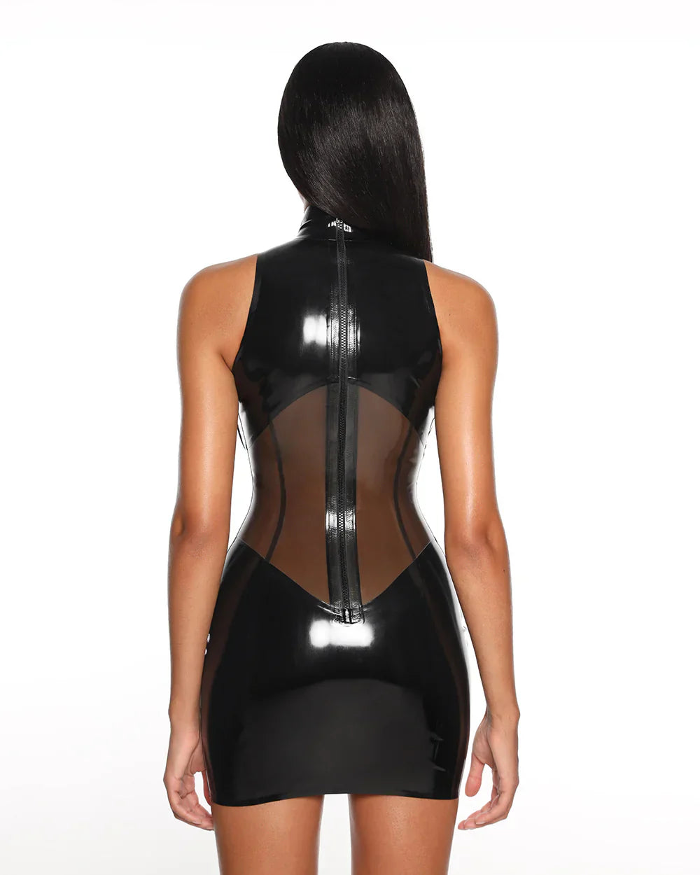 A close-up of a model is shown from the back wearing the black casey latex dress standing in front of a white 
