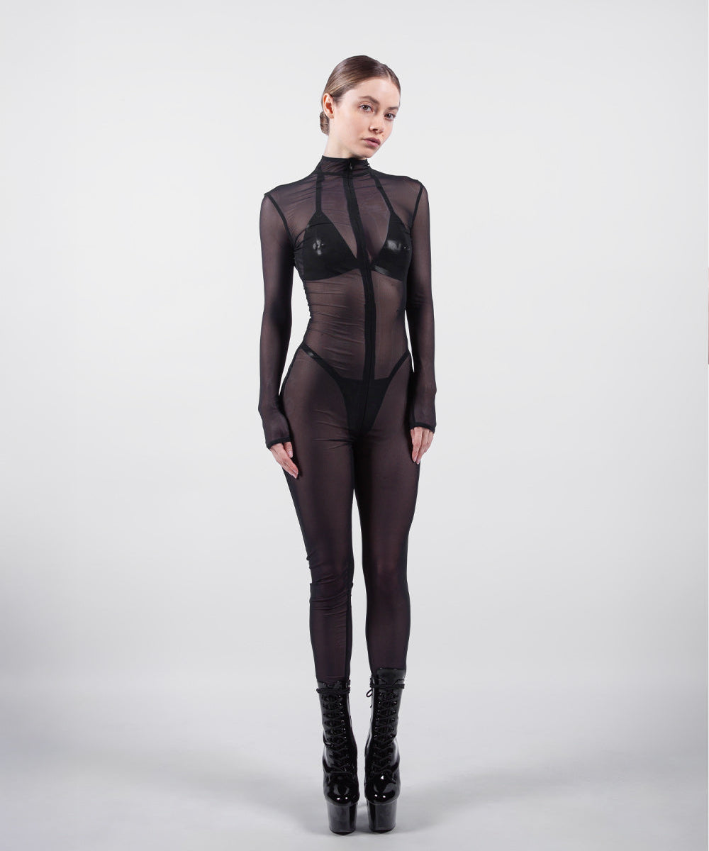 Model wearing a black bodysuit with sheer panels on a white background
