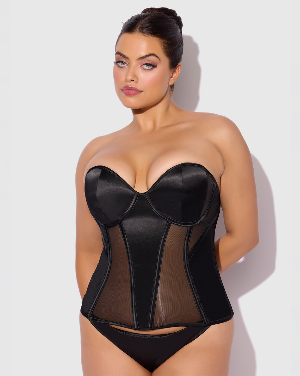 Woman wearing a black sheer corset against a white background