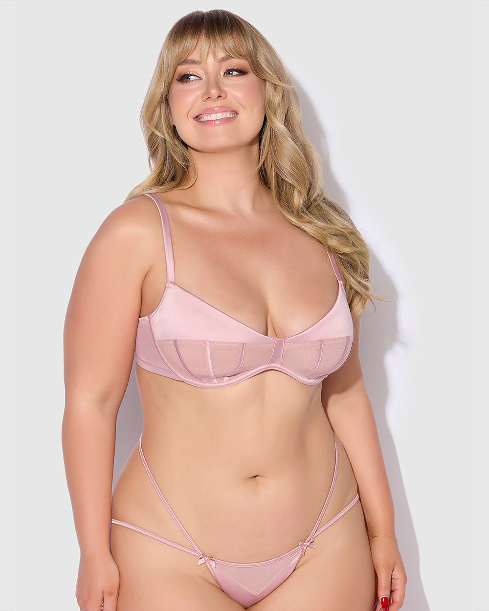 Woman wearing a pink bra and panties set against a white background