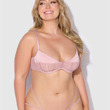 Woman wearing a pink bra and panties set against a white background