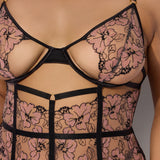 Black lace lingerie with pink floral patterns on a neutral background
