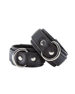 A pair of Premium Garment Leather Wrist Cuffs in black are shown against a blank background. The cuffs are made of black leather with silver hardware. They each have a D-ring and a lockable metal buckle.
