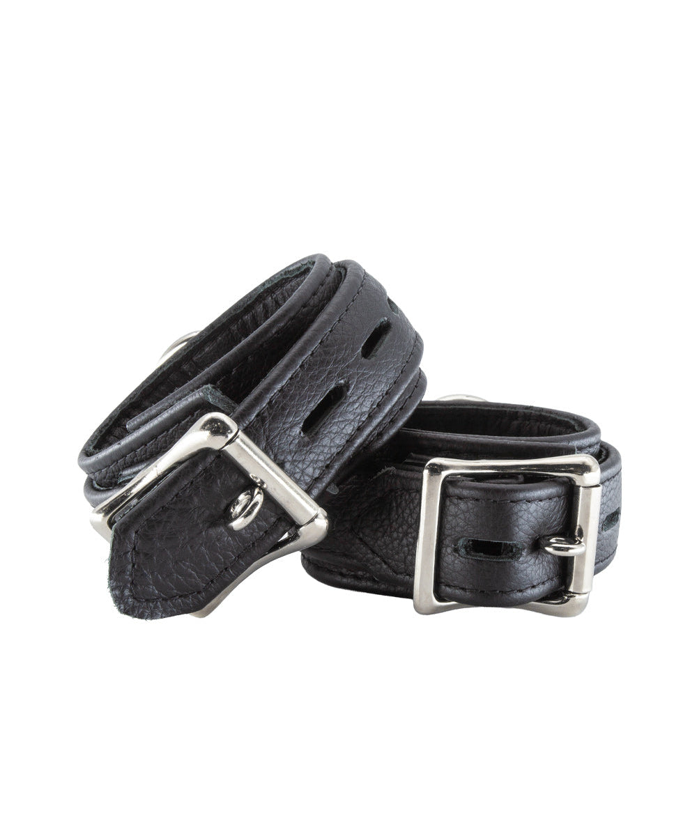 A pair of Premium Garment Leather Wrist Cuffs in black are shown from the back against a blank background. The cuffs are made of black leather with silver hardware. They each have a D-ring and a lockable metal buckle.
