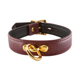 The JT Signature Collection Collar is displayed against a blank background. It is made of Bordeaux leather with gold hardware. The inside of the collar is lined in black leather. There is a small dangling O-ring in the center of the collar.