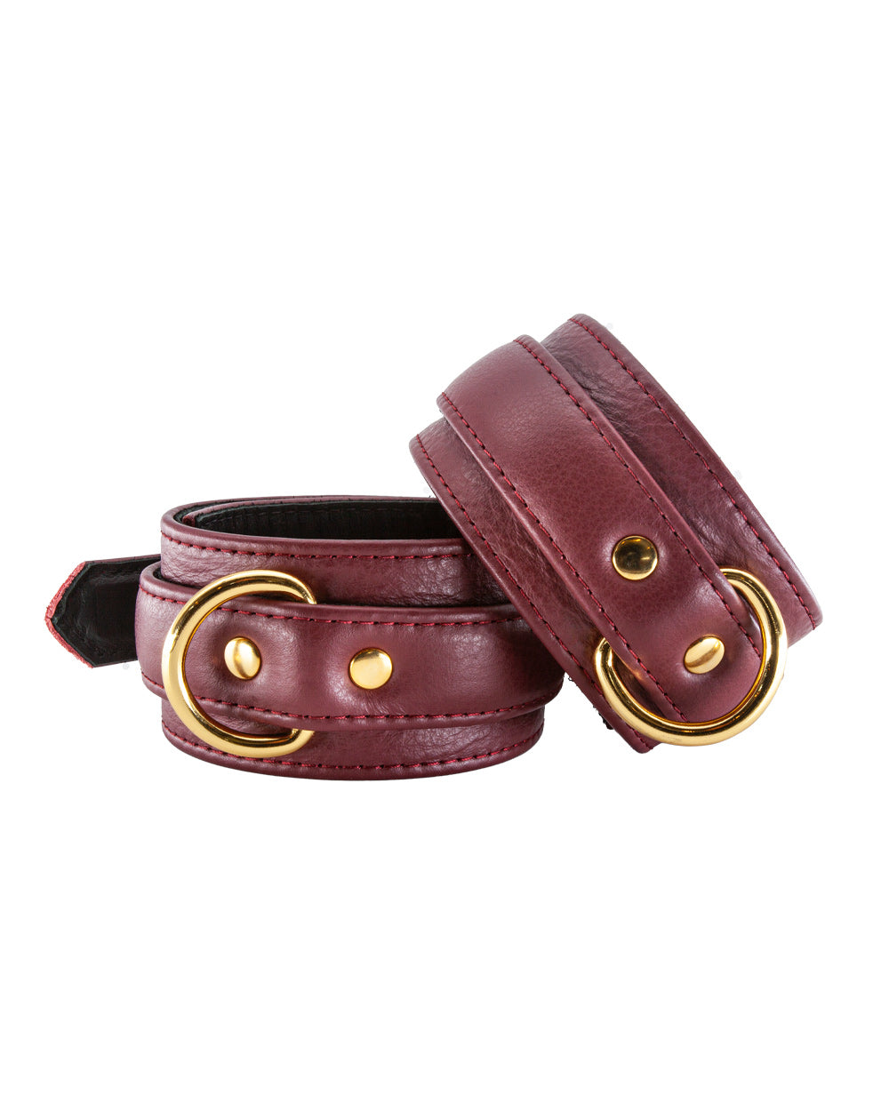 A closeup of a woman’s wrists, positioned on the pillows over her head, is shown. She is wearing the JT Signature Collection Wrist Restraints.