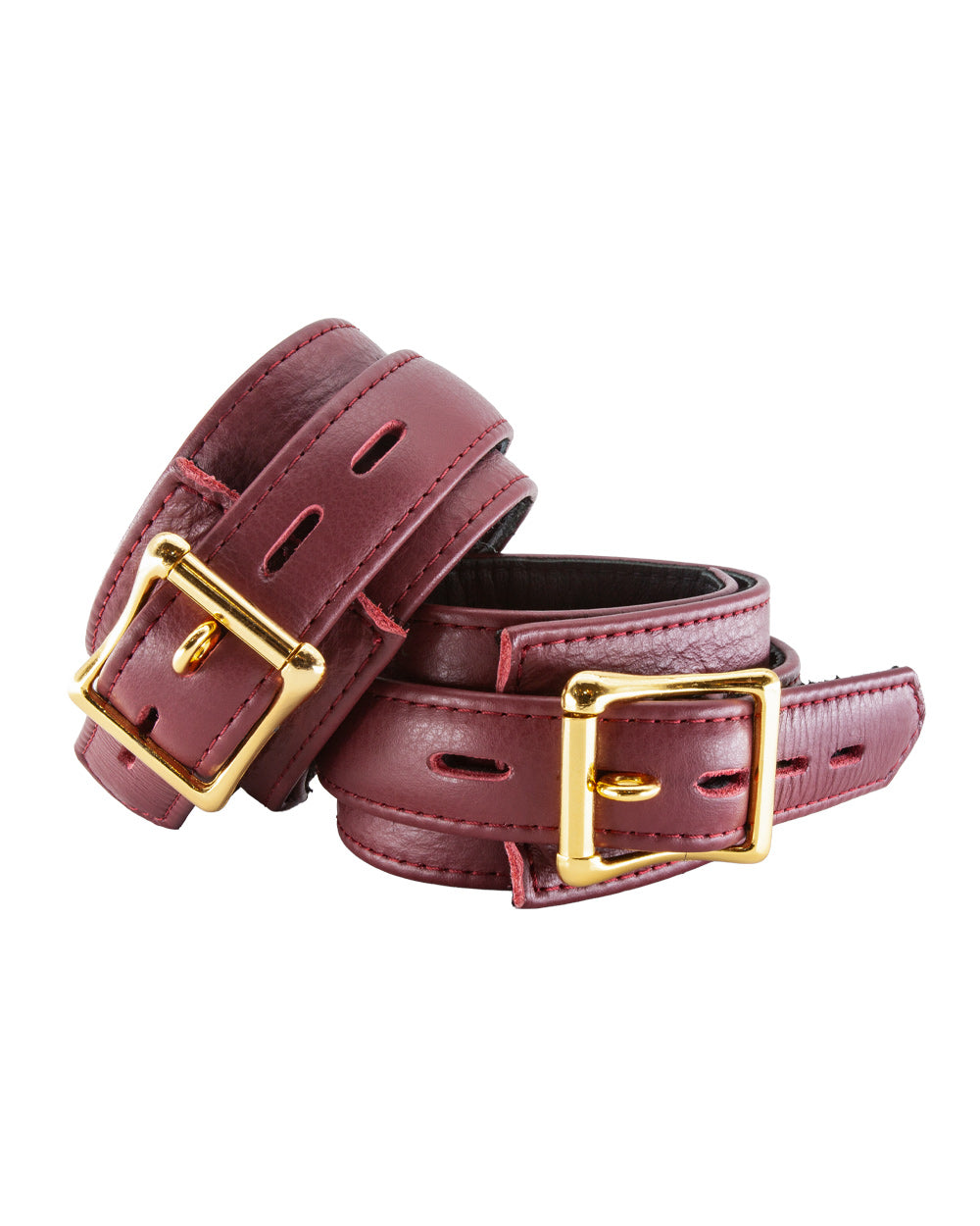 The JT Signature Collection Wrist Restraints are shown from the back against a blank background. The cuffs are made of Bordeaux leather with a black interior lining. The cuffs have a D-ring and a buckle closure. The hardware is gold.