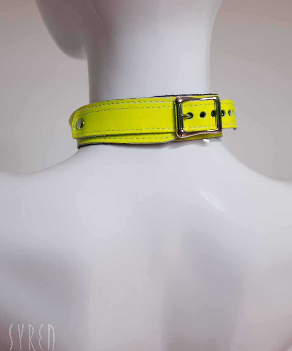 The neck buckle of the neon angel yellow leather bust harness is shown on a mannequin in front of a white background.
