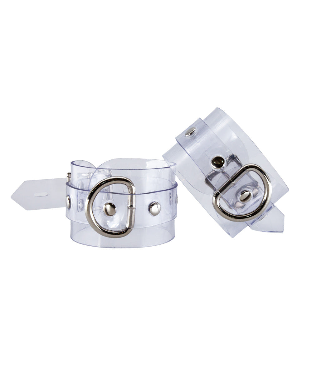 The Clear CTRL Clear Vinyl Wrist Cuffs are shown against a blank background. The cuffs are completely transparent with metal hardware. They each have a lockable buckle with an adjustable strap and a D-ring.