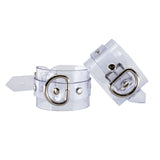 The Clear CTRL Clear Vinyl Wrist Cuffs are shown against a blank background. The cuffs are completely transparent with metal hardware. They each have a lockable buckle with an adjustable strap and a D-ring.