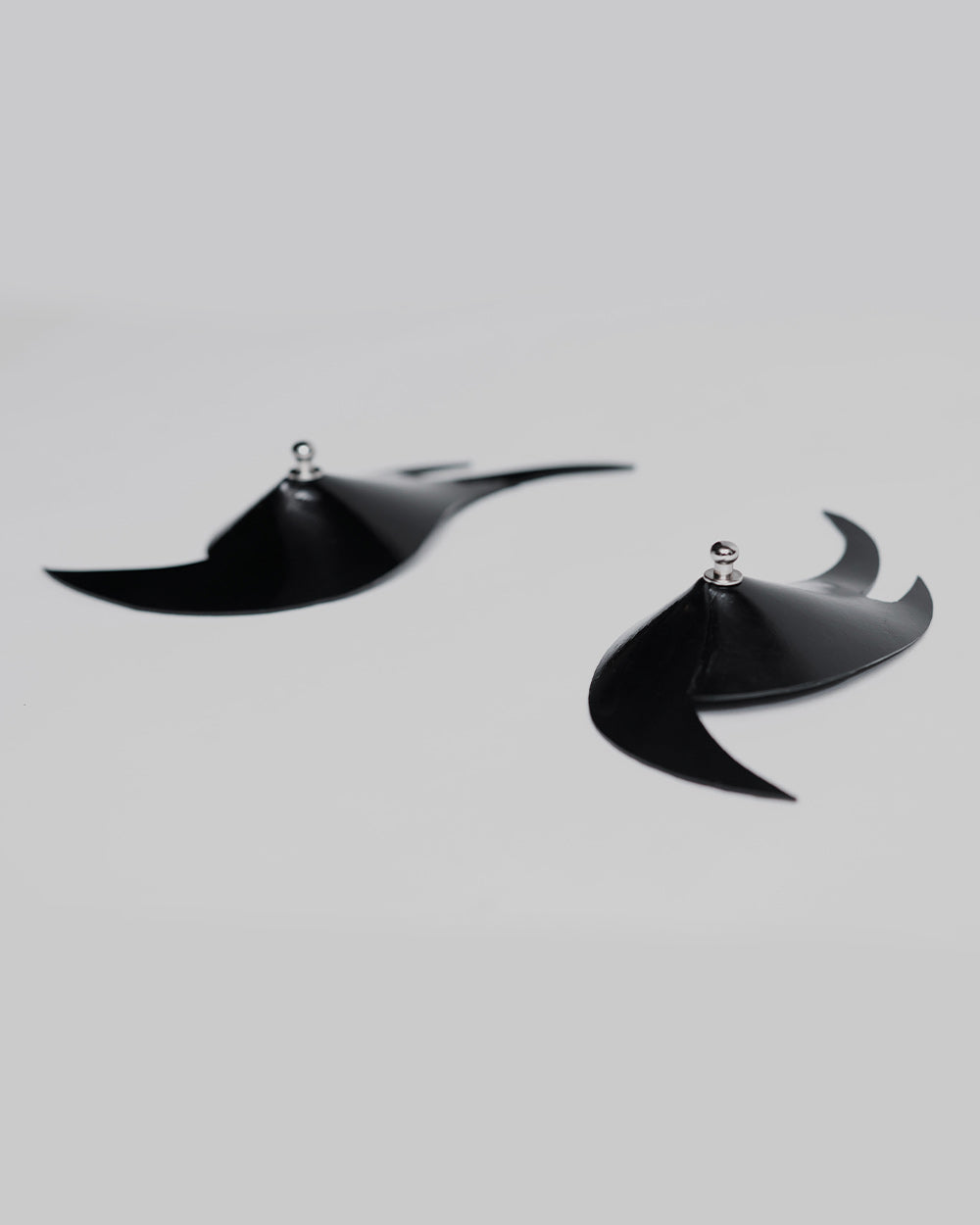 Black flame shaped pasties laying flat on a light gray background