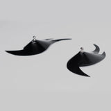 Black flame shaped pasties laying flat on a light gray background