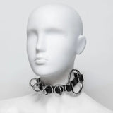 Mannequin head wearing a black chain collar on a white background