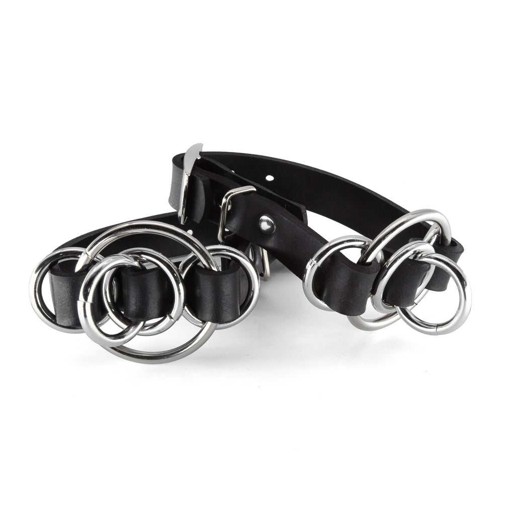 Black leather cuffs with silver rings on a white background