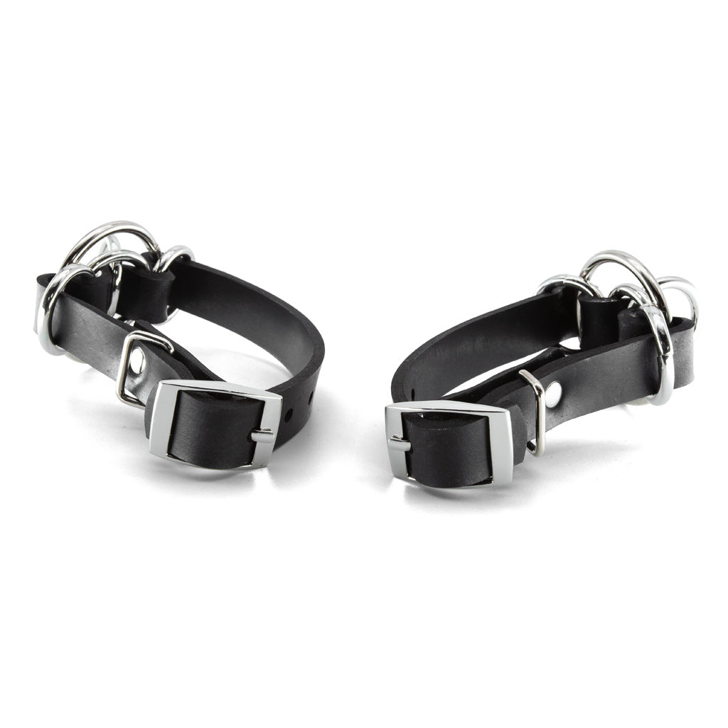 Two black leather cuffs with metal buckles on a white background