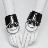 Ilaria double O ring wrist cuffs on white hands against a white background. 