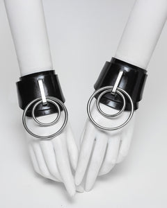Ilaria double O ring wrist cuffs on white hands against a white background. 