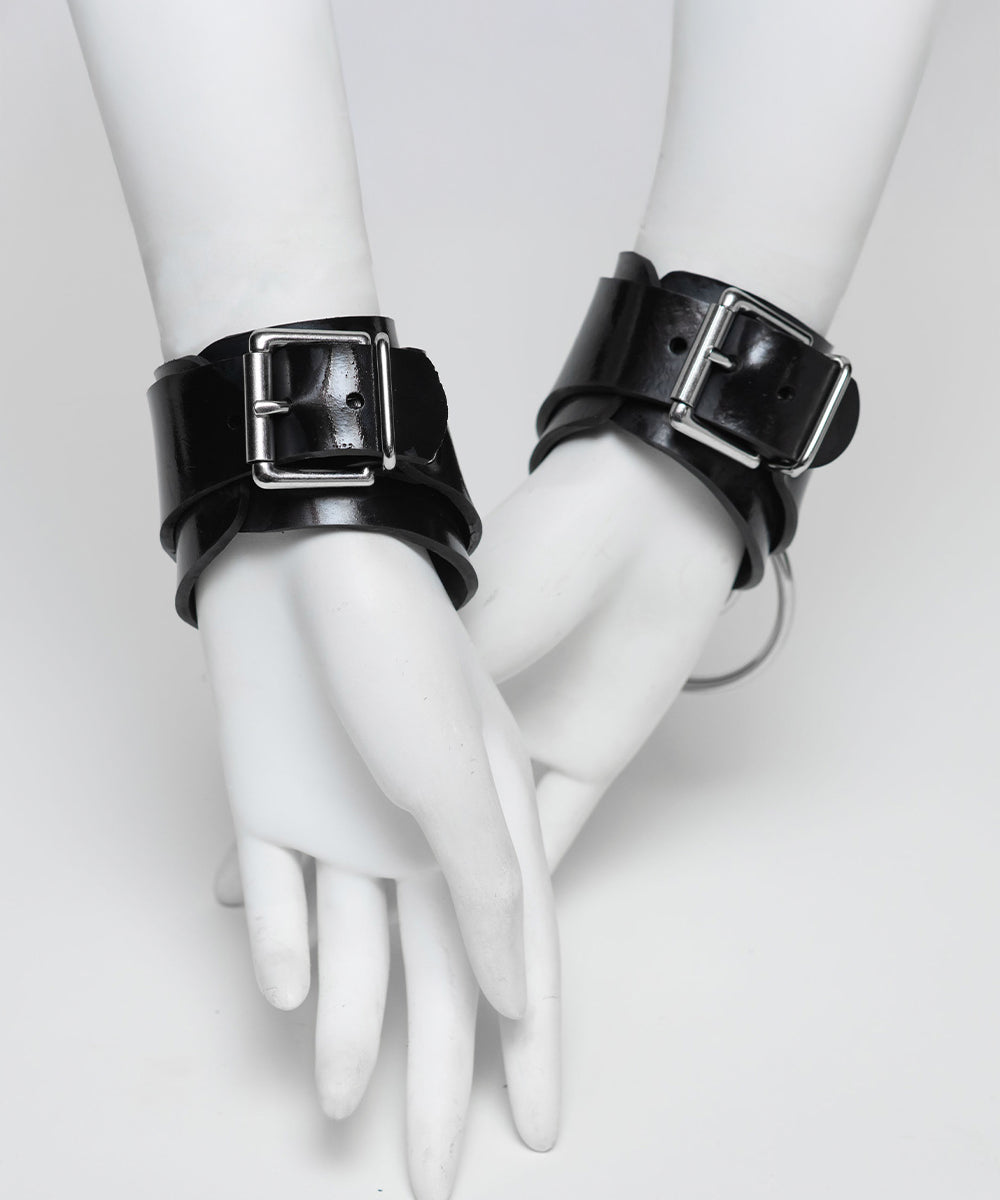 Black rubber cuffs with buckles on white mannequin hands