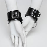 Black rubber cuffs with buckles on white mannequin hands