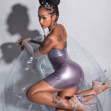 A model is shown sitting on a clear inflatable chair wearing the Syren Latex pearl Lilac halter dress against a light gray background.