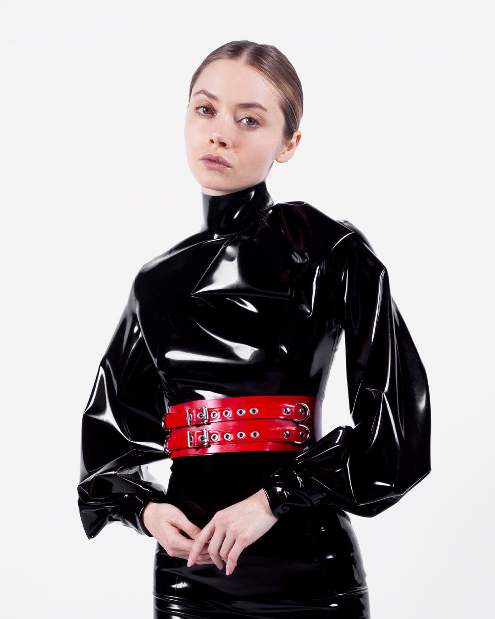 A model is shown wearing the Syren latex Garbo blouse in black. She stands in front of a white background