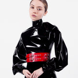 A model is shown wearing the Syren latex Garbo blouse in black. She stands in front of a white background