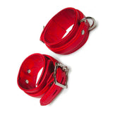 A pair of red Premium Garment Leather Ankle Cuffs are displayed against a blank background. They are made of red leather with silver hardware. Each cuff has one D-ring, and they fasten with lockable buckles.