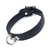 The Premium Garment Leather Collar in black is shown against a blank background. The collar is made of black leather and has silver hardware. It has a dangling O-ring in the front and a buckle fastener in the back.