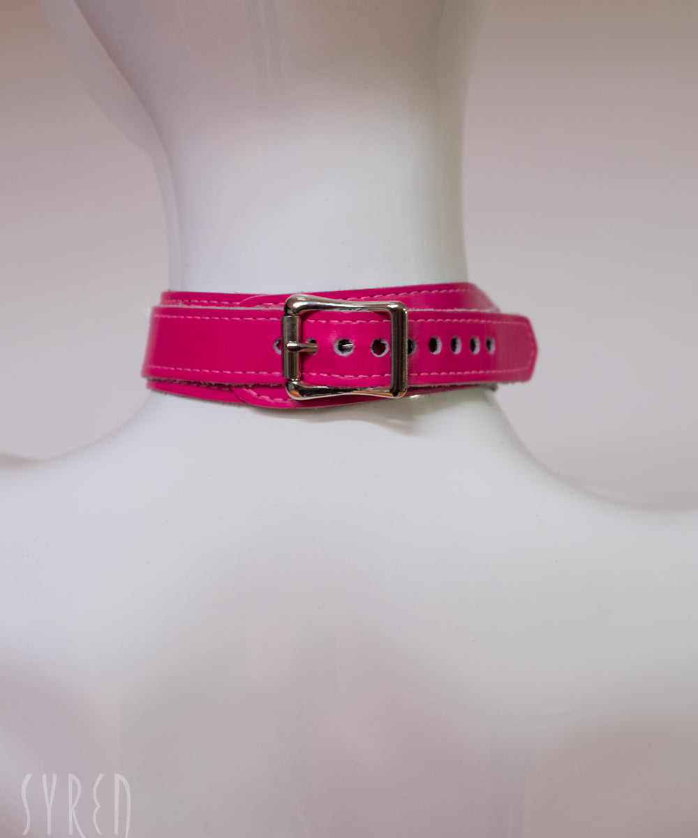 The neck buckle of the neon angel pink leather bust harness is shown on a mannequin in front of a white background