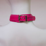 The neck buckle of the neon angel pink leather bust harness is shown on a mannequin in front of a white background