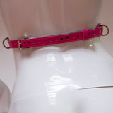 The waist buckle of the  neon angel pink leather bust harness is shown on a mannequin in front of a white background.