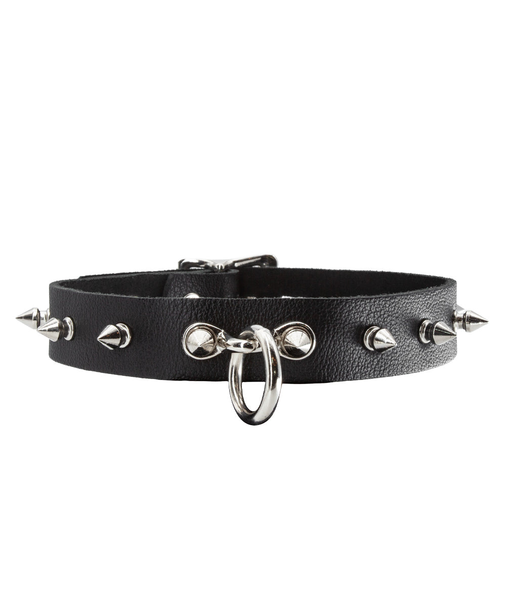 The Leather Collar with Spikes is shown against a blank background. It is made of black leather with metal hardware. There are spikes projecting outwards around the collar and a dangling O-ring in the front.