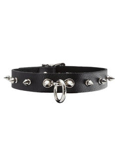 The Leather Collar with Spikes is shown against a blank background. It is made of black leather with metal hardware. There are spikes projecting outwards around the collar and a dangling O-ring in the front.