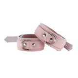 The Stupid Cute Wrist Cuffs are shown fastened against a blank background. The leather is pink with white edges and white stitching on the borders. They have a silver D-Ring and fasten with a lockable buckle.